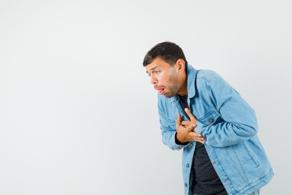 man experiencing nausea with both hands on his heart